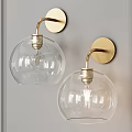 Modern Brass Wall Sconces With Clear Glass Globe Shades Mounted On Gray Wall
