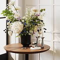 Black Vase With White And Blue Flowers Foliage On Round Wooden Table With Silver Candleholders