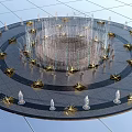 Stunning Circular Fountain With Golden Star Decorations And Transparent Columns On Gray Pavement