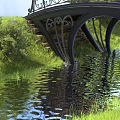 Beautiful Scenery with Arched Black Iron Bridge Over Water and Green Grass Reflections