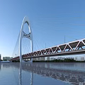 Modern Cable Stayed Bridge With Arch Structure Truss Deck And City Skyline Water Reflection