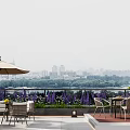 Scenic Villa Balcony With Outdoor Umbrella Dining Furniture Purple Flowers Trees And City View