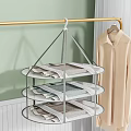 Three Tiered Metal Clothes Hanger Holding Folded Clothes with Shirt Hanging Nearby in Indoor Space