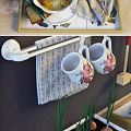 Floral Patterned Kitchenware Display On Shelves With Mugs Spatulas Oven Mitt And Bowls