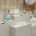 White Layered Display Shelves With Vases And Small Ornaments On Textured Wall