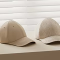 Two Beige Baseball Caps With Different Textures On Light Colored Surface And White Blinds Background