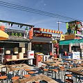 Commercial Street With Outdoor Dining Tables Umbrella Store Signs Green Plants And Fence