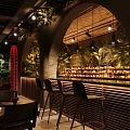 Dark Toned Bar Interior With Various Seating Green Plant Decor Soft Lighting And Wall Murals