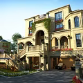 Elegant Detached Villa with Beige Exterior Arched Windows Balconies Green Plants Red Flowers and Garage