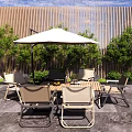 Outdoor Dining Set with Umbrella and Wooden Wall Surrounded by Green Plants in Patio Area