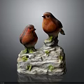Red Bird Figurines Perched On White Base With Green Moss