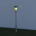 Lit Outdoor Lamp With Yellow Light Metal Pole Standing On Green Grass Against Blue Wall