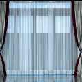 Beige Curtains with Red Tassels and Sheer White Panels for Window with Blue Sky Background