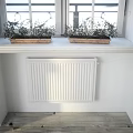 White Dining Table in Bright Room with Large Window Small Plants and Wall Decorations