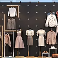 Fashionable Clothes Display With Mannequins And Different Hanging Styles On Store Wall