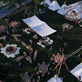 Lively Camping Site With Tents Bonfire Wooden Tables And People Gathering