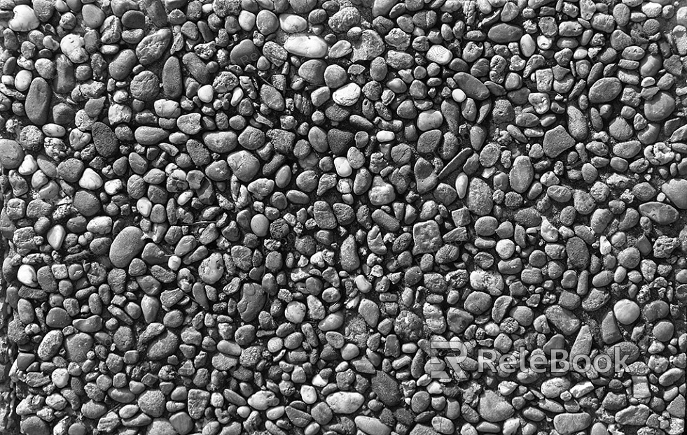 A gritty, textured image of gravel, showcasing small stones and pebbles in various shades of gray and brown, set against a backdrop of what appears to be a concrete or asphalt surface.