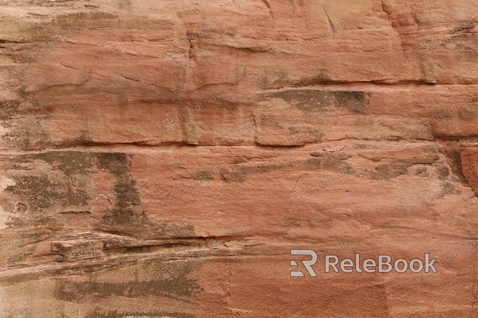 A rugged, gray-brown rock surface with distinct cracks and uneven texture, resembling a close-up of a boulder or cliff face.